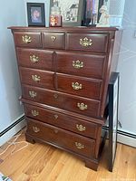 Full front view of brown wood six-drawer dresser with brass hardware.