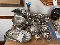 Wide shot of the entire set showing all items on a wooden surface including vase, pitcher, shakers, bowls, ladle, and tray