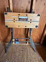 Front view of folded Black & Decker Workmate work table showing metal frame and wooden slats with wear.