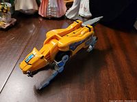Front angled view of the Sabertooth Tiger Zord leg showing bright orange color, grey mechanical legs, and decals on the side.