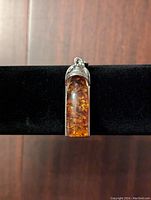 Front view of amber pendant showing polished amber gemstone with natural inclusions and silver-tone top detail and loop.