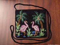Front view of small beaded cocktail purse with detailed flamingo and palm tree beadwork, long beaded crossbody strap laid flat