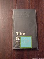 Front view of Kate Spade The Short List black notepad sealed in plastic with brand label.
