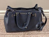 Front and side view of the dark blue Liz Claiborne purse showing the brand name on exterior with handles and attached crossbody strap.