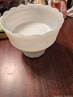 Side view of the milk glass pedestal dish showing the scalloped edges and pedestal base.