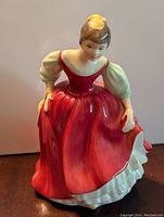 Front and side view of Royal Doulton Fair Maiden porcelain figurine in red dress with yellow hat detail