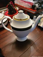 Porcelain Spode Chardonnay coffee pot with green and gold decorative banding, shown from one side on a wooden surface.