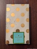 Front view of one small Kate Spade notepad detail showing gold dots and front label.