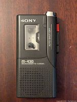 Front view of the black Sony M-430 Microcassette Voice Recorder showing cassette window, controls and speaker grille.