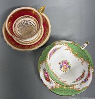 Two vintage Paragon teacups with matching saucers, one red and gold, the other green with floral pattern and gold gilt.