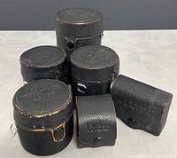 Five leather lens cases (three cylindrical, two small)