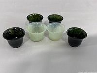 Front view of six jade cups showing varying shades of green.