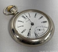Antique Waltham pocket watch showing front dial with Roman numerals and 24-hour time scale, second hand subdial at 6 o'clock, silver-tone case, gold crown and loop.