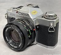 Front angle view of Canon AV-1 camera with lens attached showing brand and model markings along with 'Passed' sticker.