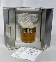 Front view of crystal flacon with frosted lion head cap inside open original box, instruction leaflets displayed
