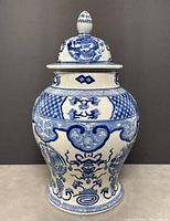 Front view of large blue and white Asian ginger jar with lid, showing detailed hand painted dragon and floral motifs.