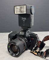 Oblique front-right view of Ricoh XR-10M camera with Vivitar 2800 flash attached showing lens and strap.