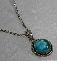 Close-up of the blue topaz pendant with silver rope border showing the stone's clarity and color.