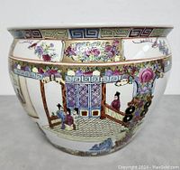 Front side of the fish bowl planter showing detailed hand painted Asian figures and floral motifs, geometric rim border.