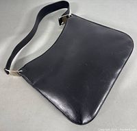 Front view of black leather shoulder bag laid flat