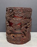 Front view of cylindrical bamboo holder with carved dragon and cloud motif, showing detailed open carving and patina.