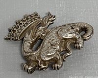 Front view of the silver plated crowned salamander brooch showing detailed texture and crown design.