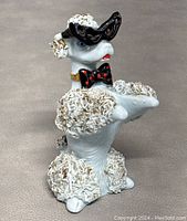 Front and side views of vintage poodle figurine showing textured curls, hat, and bow tie details.