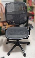Front view of black all-mesh office chair with padded armrests and mesh back and seat