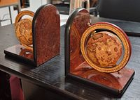 Pair of vintage rotating globe bookends with antique map-styled globes encased in brass-colored rings and mounted on polished wooden bases.