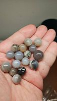 Multiple natural agate druzy spheres in hand, showing variety of colors and patterns.