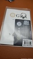 Photo of the ring with GRA certification card, showing the gemstone and ring band.