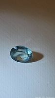Oval light blue aquamarine gemstone on white background showing transparency and facets