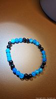 Photo of natural ocean blue agate and black onyx round bead bracelet on a tan surface.