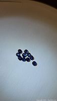 Top view of ten small round royal blue cabochon sapphires on white background showing uniform shape and size.