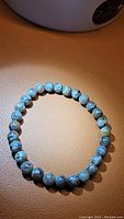 Natural Yooperlite bracelet laid flat on a tan surface, showing round polished beads in grey tones.