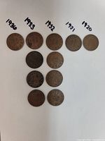Top view of all five coins arranged in a row with dates handwritten above each coin: 1920, 1921, 1932, 1933, 1936.
