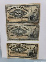 Front sides of three 25 cent Dominion of Canada notes dated 1900, showing detailed typography and seated figure illustration.