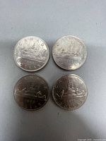 Obverse and reverse sides of four Canadian silver dollar coins from 1968, 1969, 1972, and 1975 showing canoe scene and Queen Elizabeth II portrait.