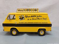 Side view of yellow die-cast model van with NAPA Auto Parts promotional graphics and Balkamp display box on top