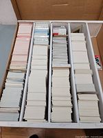 Large box filled with numerous stacks of hockey cards organized in rows, showing many cards with blank backs or stock backs.