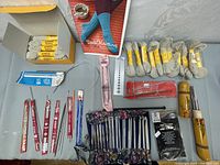 Wide view of knitting needles, crochet hooks, yarn skeins, sock knitting kit, and accessories spread on a surface.