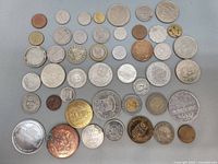 Overview of multiple coins and tokens arranged on a flat surface showing variety in size, material and design.