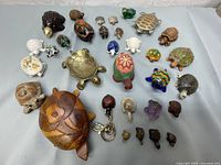 Wide view of the turtle figurine collection showing different materials and sizes, including wood, metal, ceramic, and plastic.