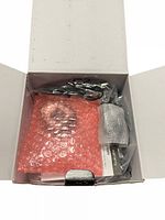 Open box showing Garmin branded packaging with accessories inside including cables, manuals, and a subcomponent sealed with bubble wrap.