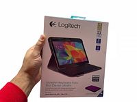 Single Logitech Ultrathin Keyboard Folio case in original packaging held in hand, showing front of box with tablet image and product details