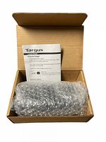 Targus laptop charger wrapped in bubble wrap inside a cardboard box with an instruction sheet visible.