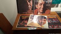 Group photo of 6 vinyl LP albums arranged on a wooden sideboard, featuring portrait covers of Dean Martin and Frank Sinatra, along with Don Ho albums.