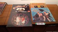 Four vinyl albums including Mama's and Papas, The 5th Dimension, Peter Paul & Mary, arranged on a wooden surface.
