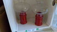 Pair of red colonial hurricane glass candle holders placed side by side on a white shelf.