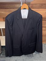 Solid black men's suit jacket hung on a wooden hanger, showing the front exterior view.